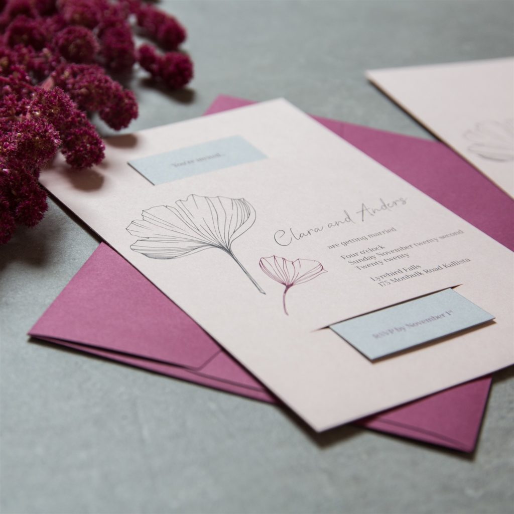 Prioritise photo over video.  Photography of pink wedding invitation with ginkgo leaf design