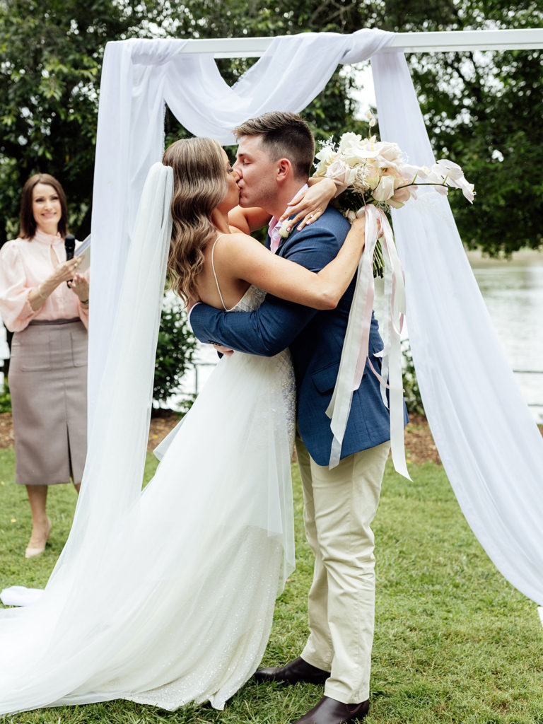 Bride and groom kissing at the altar in a park with a celebrant.