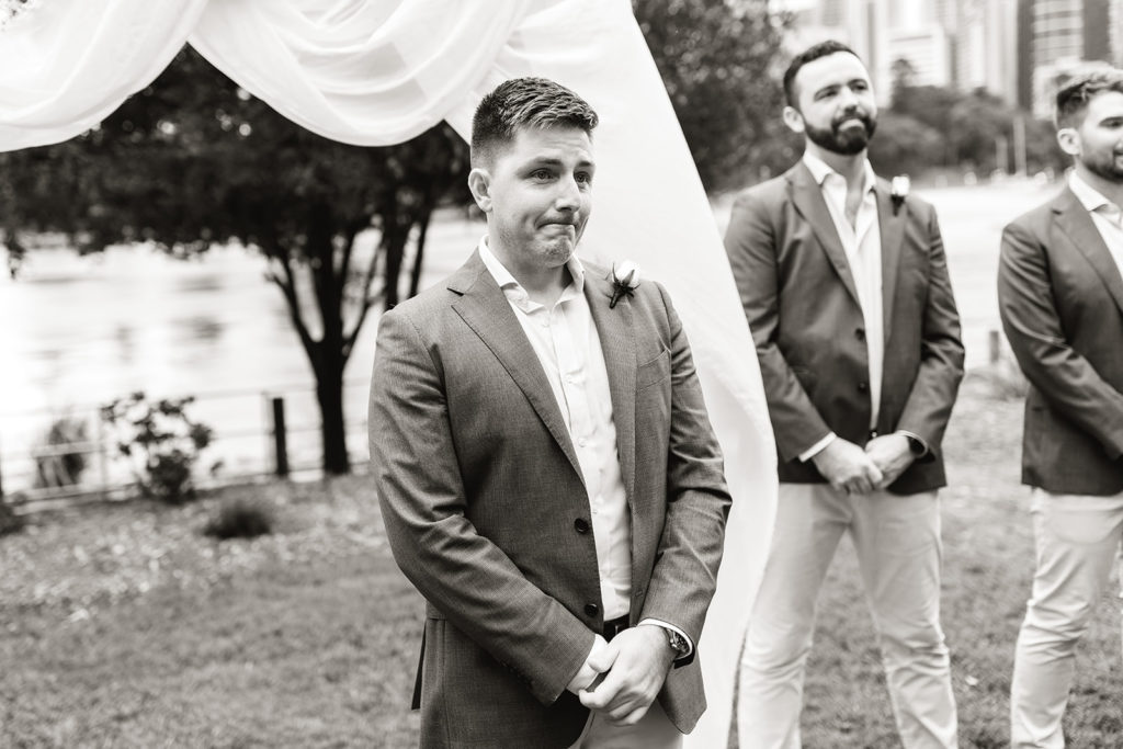 Groom waiting at the wedding alter, in a park with a flowing cloth backdrop.
