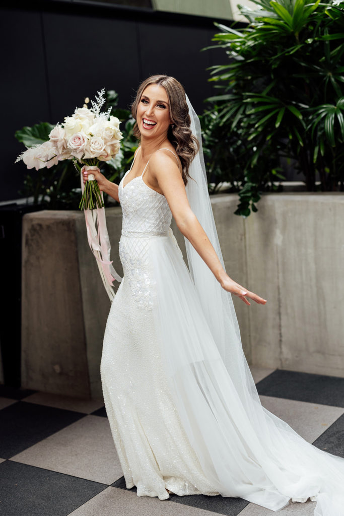 Bride having fun and smiling on her wedding day, holding her bouquet with white flowers