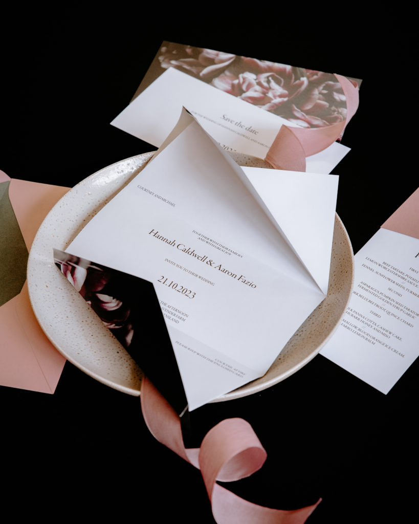 Origami invitations with black and pink floral and classic elegant text inside.
