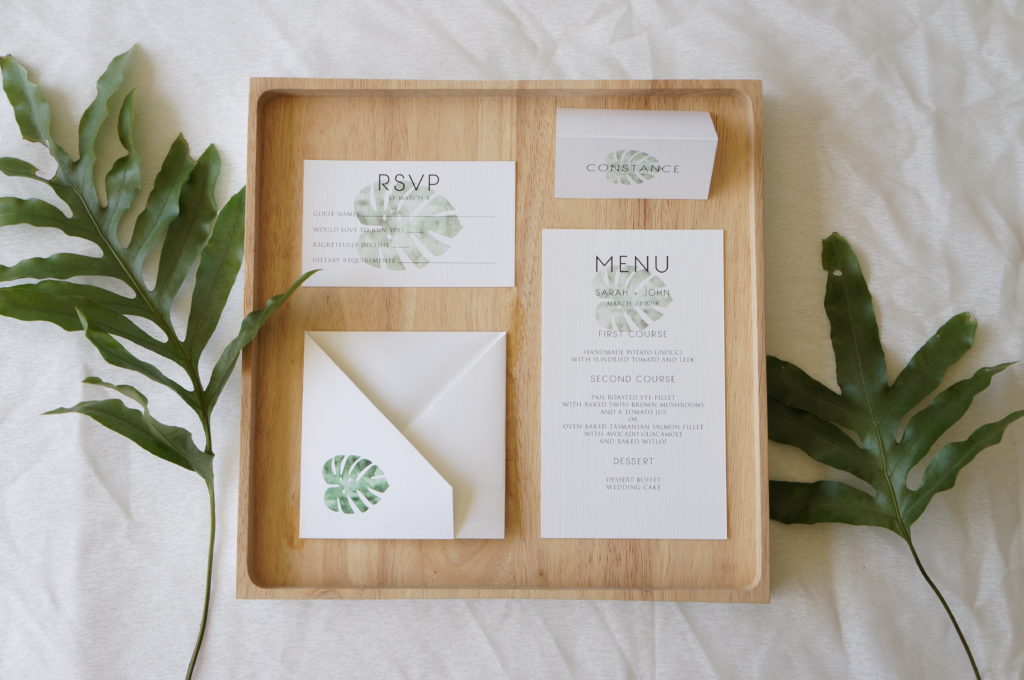 White wedding stationery suite with green monstera leaf design and origami folds