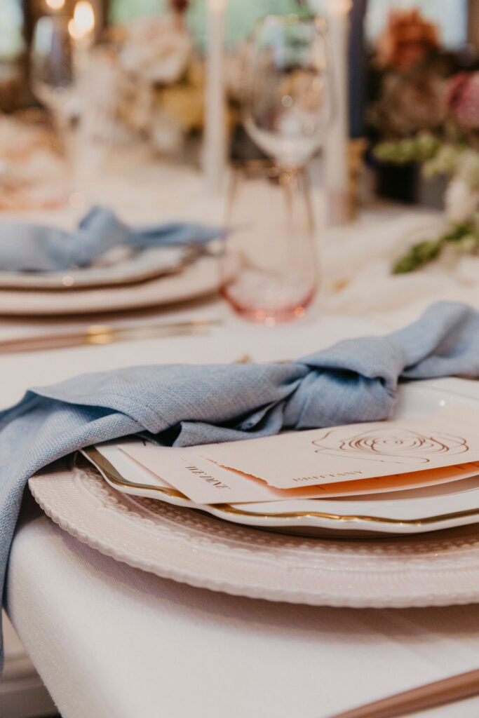 On the day stationery includes menus and place cards, which can be layered like this sewn booklet alongside the blue napkin.