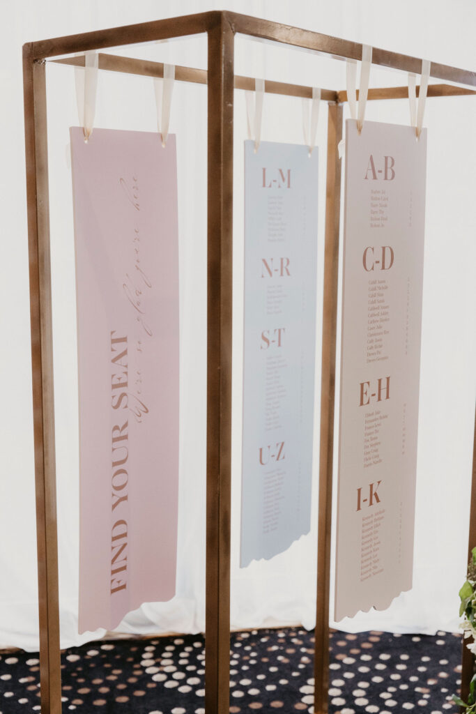 A close up of a three-piece table seating chart with names in alphabetical order for a wedding reception