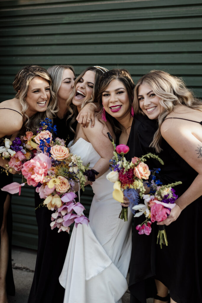 A bride and her four bridesmaids hold bright colourful wedding bouquets.