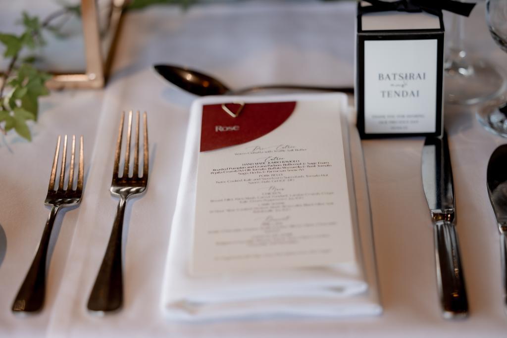 White and burgundy wedding menu and place cards at an elegant wedding reception.