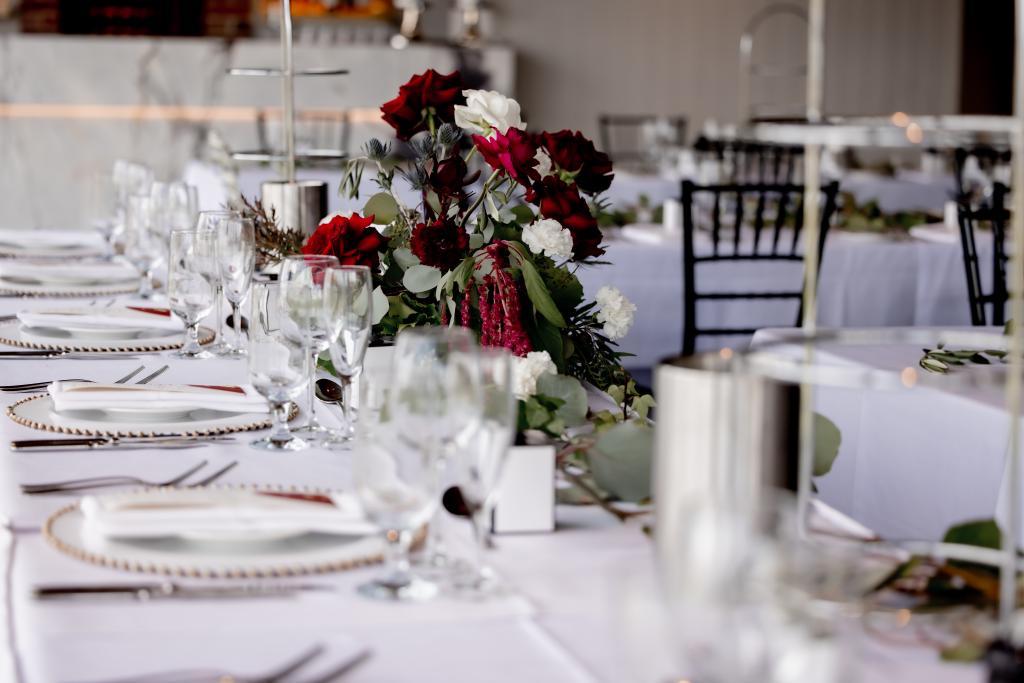 Elegant and refined wedding reception with burgundy and ivory roses and greenery.