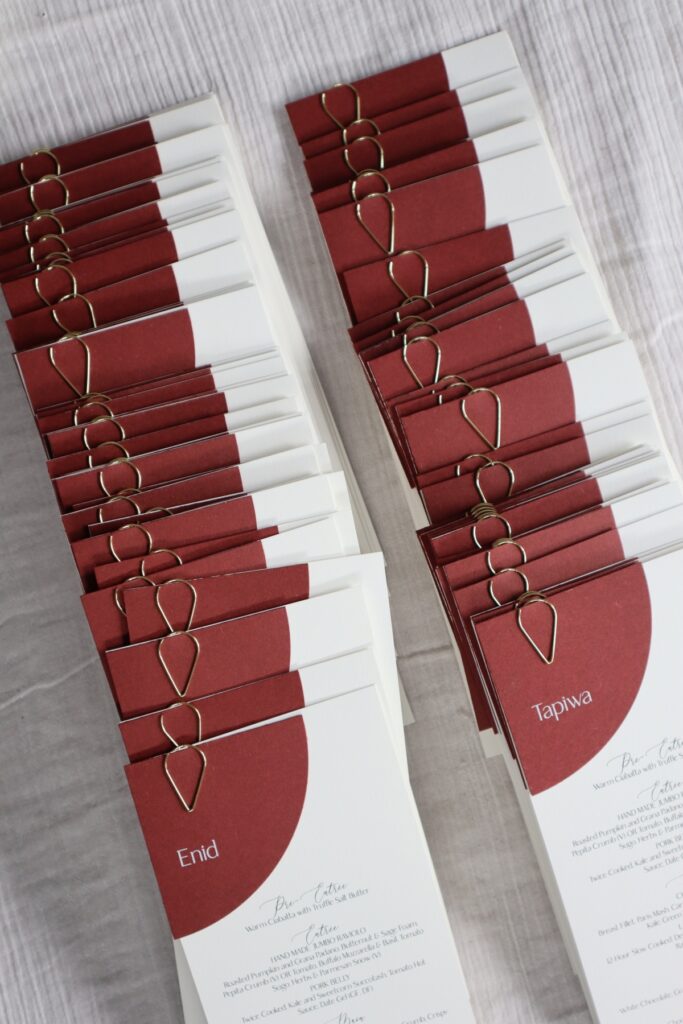 Ivory and burgundy wedding menus with a script font and gold teardrop clasps.