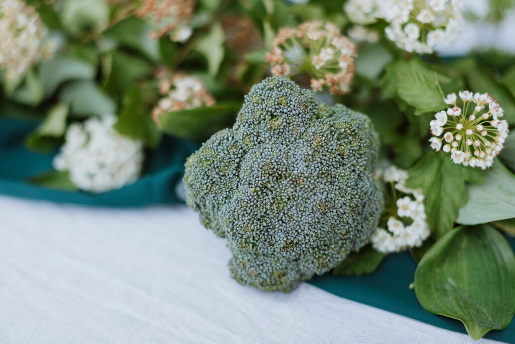 Wedding reception table styled with broccoli and green foliage.