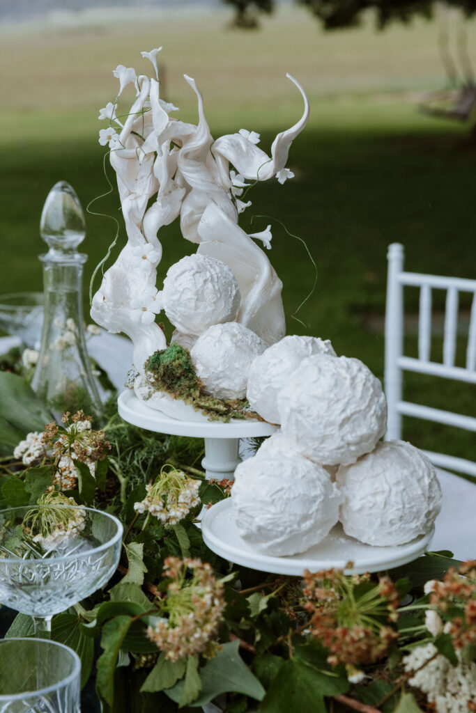 White artistic wedding cake sculpture with balls of cake covered in white icing.