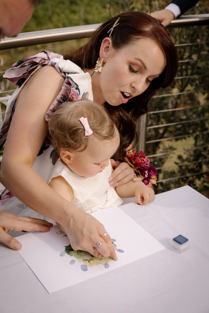 A bride and a child creating a piece of art with their fingerprints for a wedding ceremony.