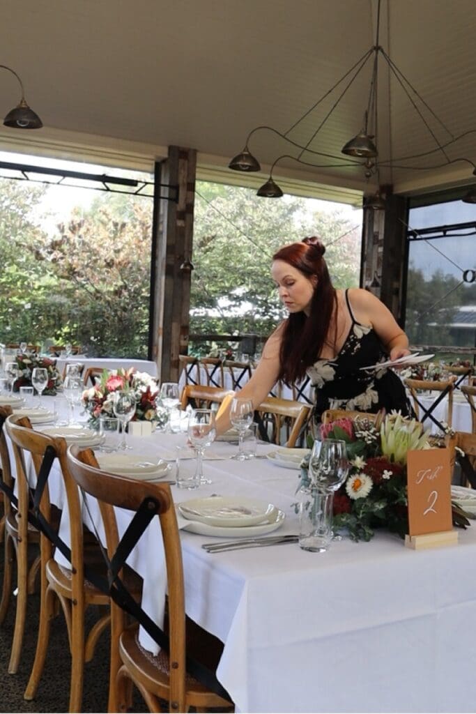 A woman arranging wedding stationery at a wedding reception at Flowerdale Estate.