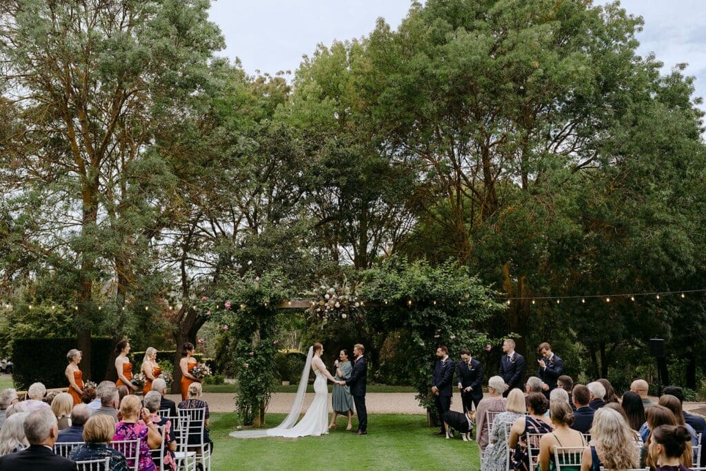 A couple getting married on a lawn in front of all their guests.