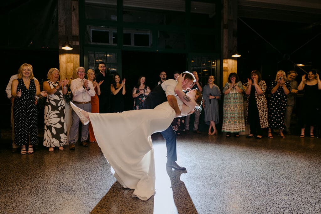 A bride and groom having their first dance in front of all their guests.